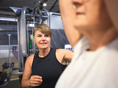 Woman Coaches Another Woman at Gym During Workout Session