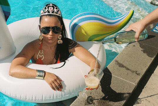 Woman Relaxing on Pool Float While Wine Is Poured
