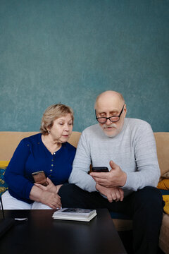 Senior couple connecting with smartphone and photo album