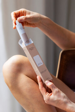 Woman Holding Skincare Cream Tube Over Knee