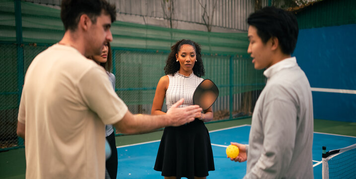 Diverse friends discussing pickleball strategy and rules on court