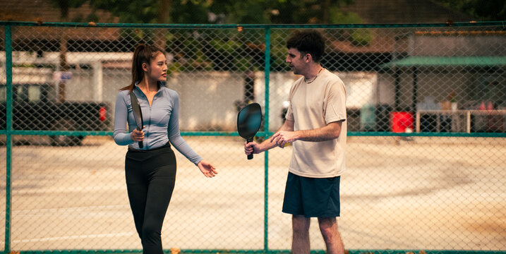 Young couple learning pickleball together on court enjoying the match