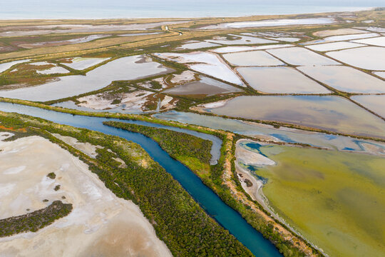 Narrow creek running between ponds at a coastal salt farm