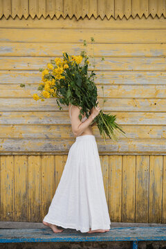 Woman holding big bouquet of yellow flowers.