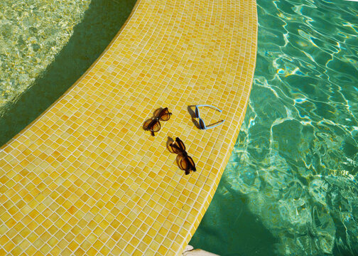 Sunglasses Resting on a Yellow Tile by the Poolside in Sunlight