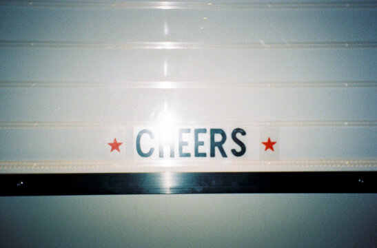 Flashy film photo of Welcoming Sign Reading "Cheers"