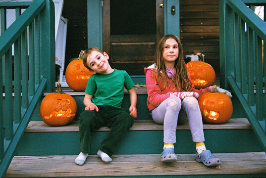 Kids on the porch with pumpkins at Halloween