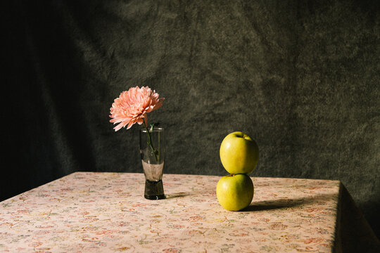 A pink chrysanthemum flower and two green apples