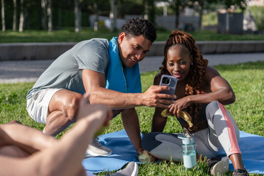 Friends sharing phone content while relaxing outdoors