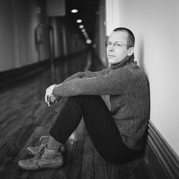 Portrait of a man sitting on a wooden floor