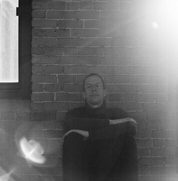 Portrait of a man sitting against a brick wall