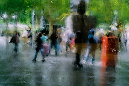 Abstract view through rain-streaked window of people walking