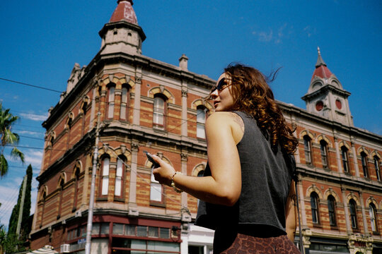 Woman using smartphone near historic building in Melbourne, VIC 