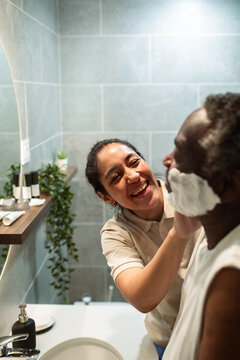Caregiver helps senior man shave in home bathroom