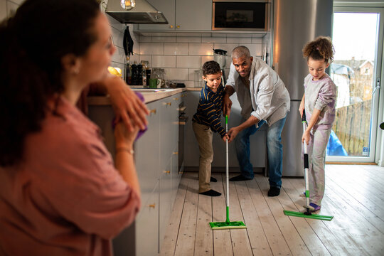 Father and children mopping kitchen floor at home