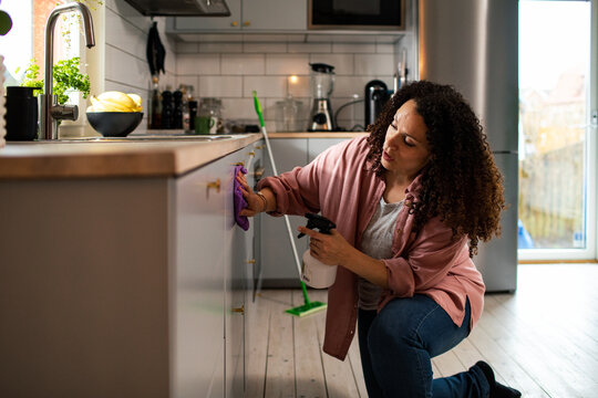 Woman cleaning kitchen cabinets at home