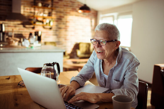 Smiling senior woman using laptop in home kitchen