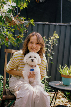 Woman with dog on her lap on the backyard patio 