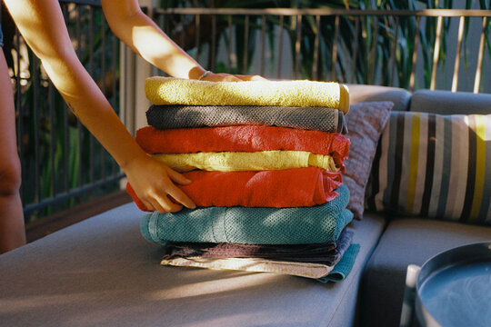 Woman's hand reach for a neat stack of folded towels 
