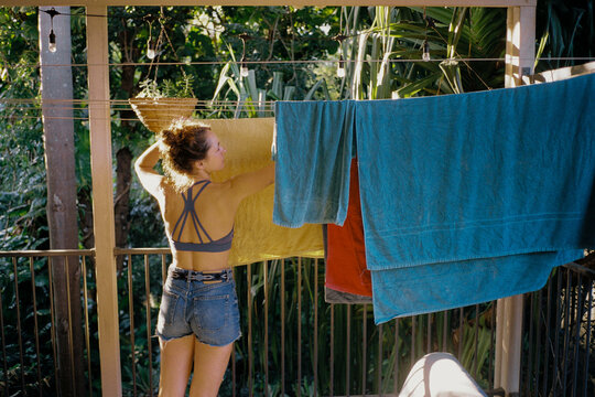 Woman hands colorful towels on clothesline 