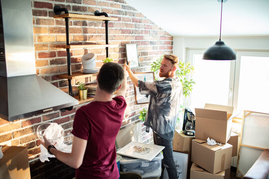 Couple hanging pictures in new apartment kitchen