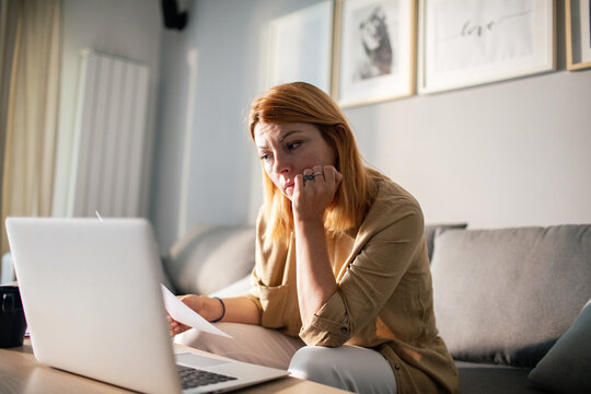 Concerned woman reviewing bills on laptop at home