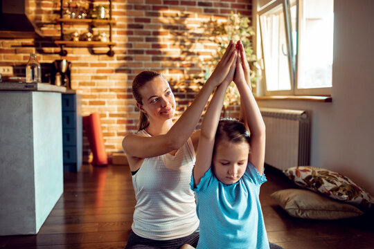 Mother guiding daughter in yoga at home