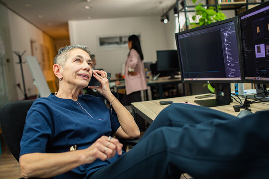 Senior woman talking on phone at modern office desk