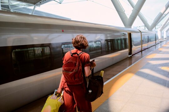 Traveler Waits at Train Station With Bags in Hand