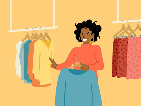 Smiling woman choosing stylish clothes in modern boutique