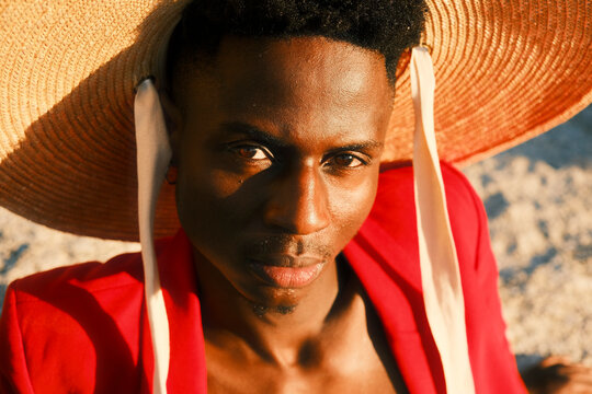 Young man in red clothing and straw hat posing on coastal rocks