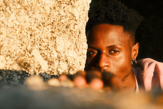 Young man looking through rocky foreground in warm sunlight