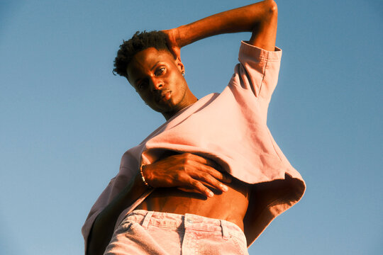 Stylish young man in colorful clothing posing by the sea 