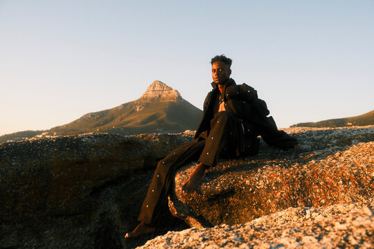 Stylish young man in black clothing posing by the sea 