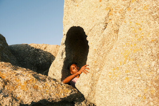 Young man resting inside rocky formation under warm sunlight