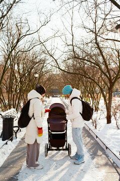 Couple with a stroller talk in a snowy park during winter