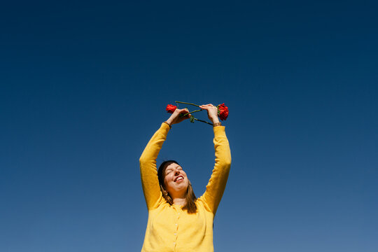 young woman holding red roses in bright sun. 