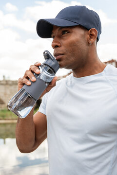 Man drinking water from reusable bottle outdoors