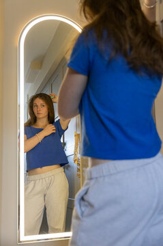 Teen combing hair in bedroom at Home 