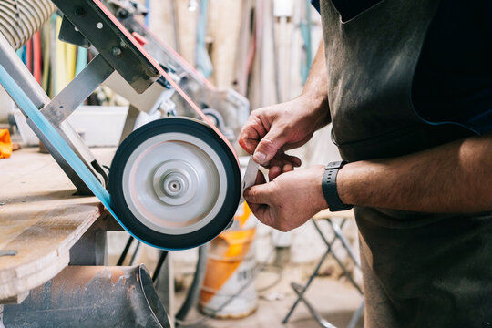Craftsman grinding a metal knife blade using a belt sander