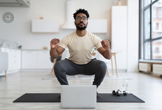 Virtual fitness and online training Man doing squats at home with laptop for workout class telehealth and remote