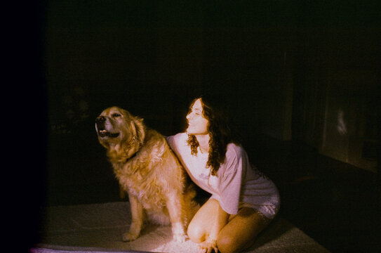 Woman smiles and kneels beside a dog at home 
