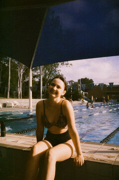 Woman smiles sitting at the swimming pool 