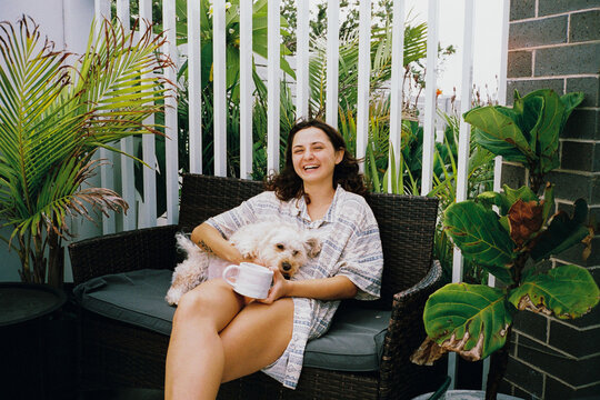 Woman laughs sitting at the patio with the dog 