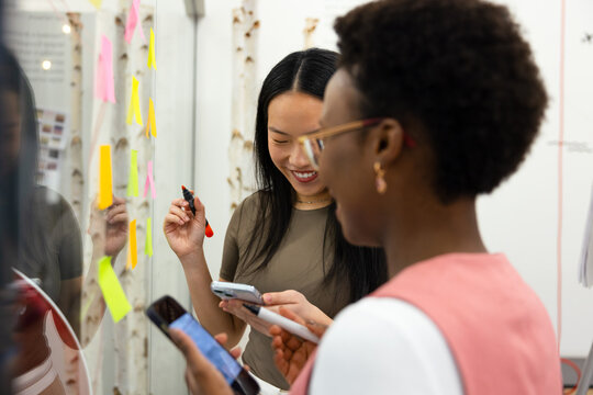 Two multiethnic women in collaborative brainstorming in modern office
