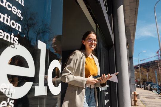 Young woman smiling outdoors holding papers