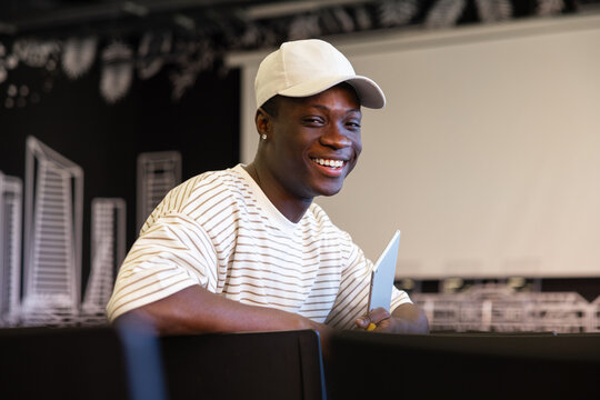 Smiling young man in casual clothing with laptop