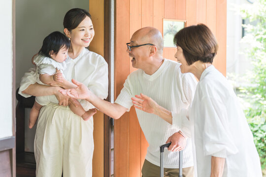 A daughter and granddaughter welcome their parents, who have come to visit or travel from the countryside, at the front door.
