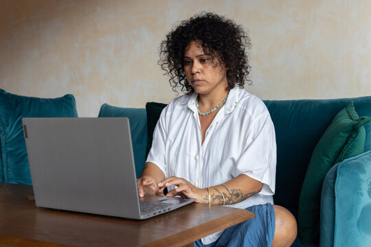 focused woman working on laptop computer, sits on couch