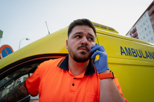 Paramedic Talking On Phone Beside Ambulance